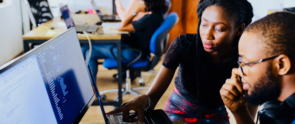 Woman explaining code to man at computer